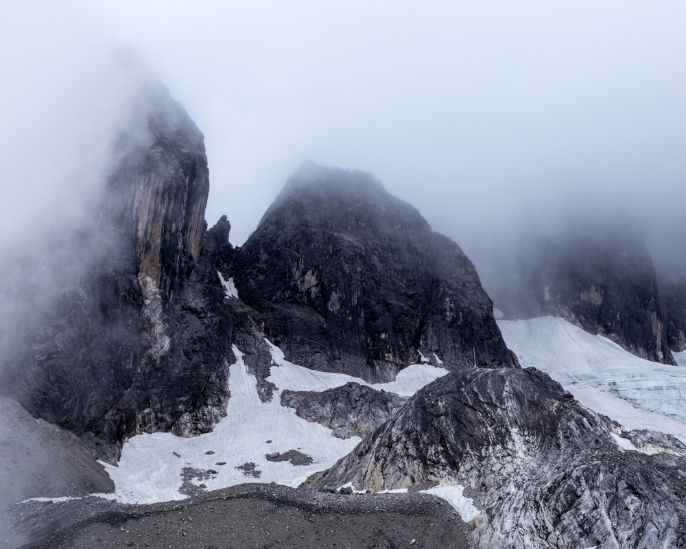 Top of mountain with mist black rock and white glacier. 